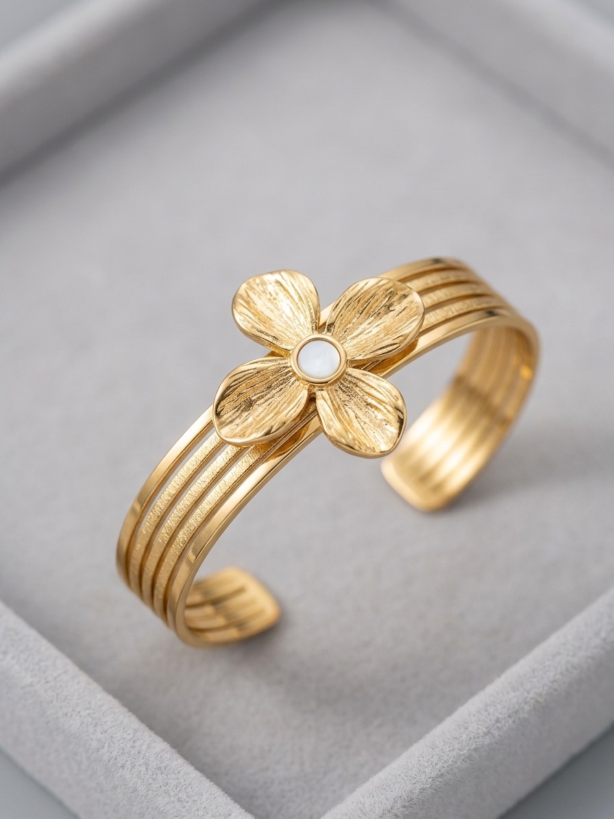 Manchette dorée ornée d'une fleur au cœur nacré, posée dans son écrin Atelier Kymia